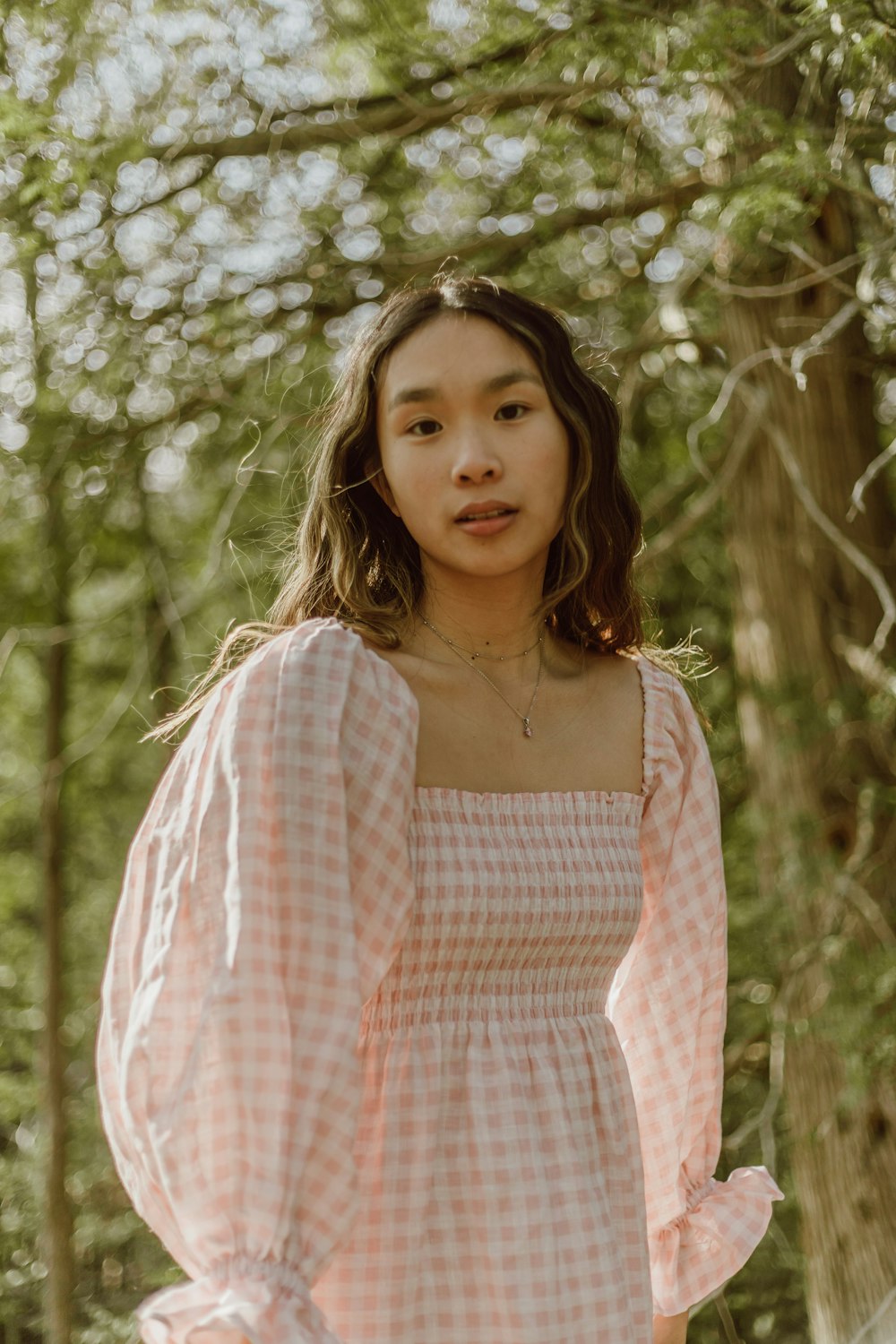 woman in white and red plaid off shoulder long sleeve shirt standing near white flowers