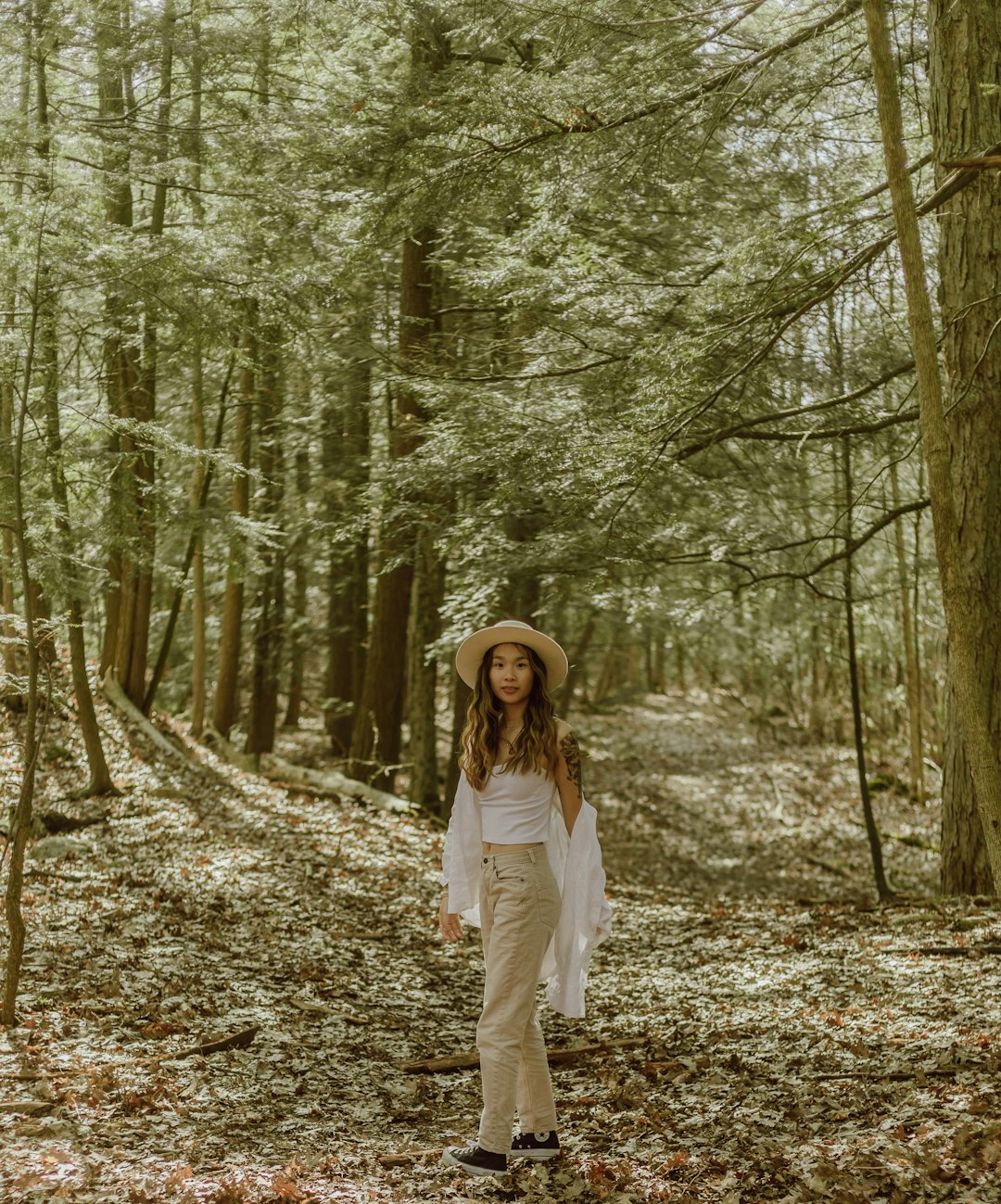 woman in white long sleeve shirt standing in the middle of forest during daytime