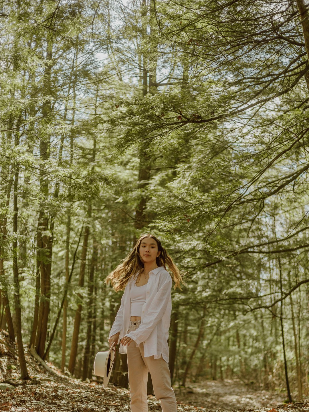 woman in white long sleeve shirt standing in the woods during daytime