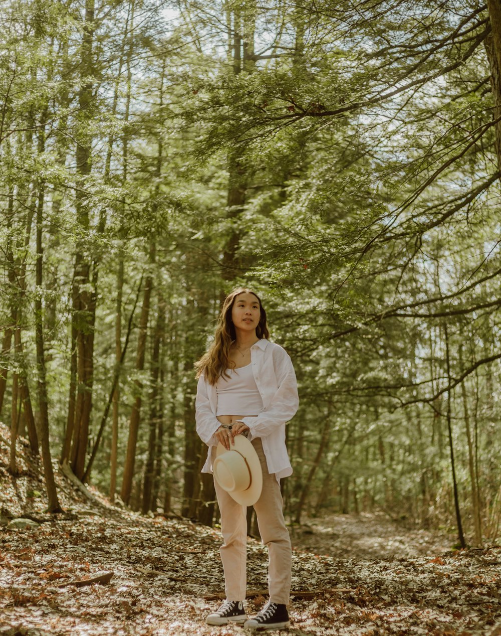 woman in white long sleeve shirt and white skirt standing on forest during daytime