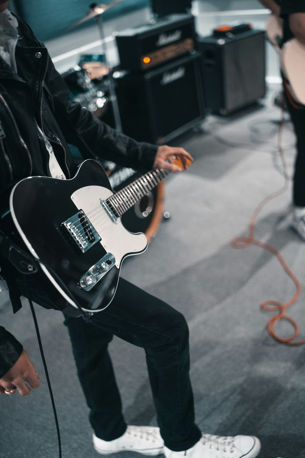 man in black jacket playing white electric guitar