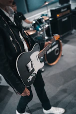 man in black leather jacket playing electric guitar