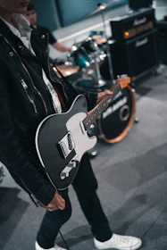 man in black leather jacket playing electric guitar