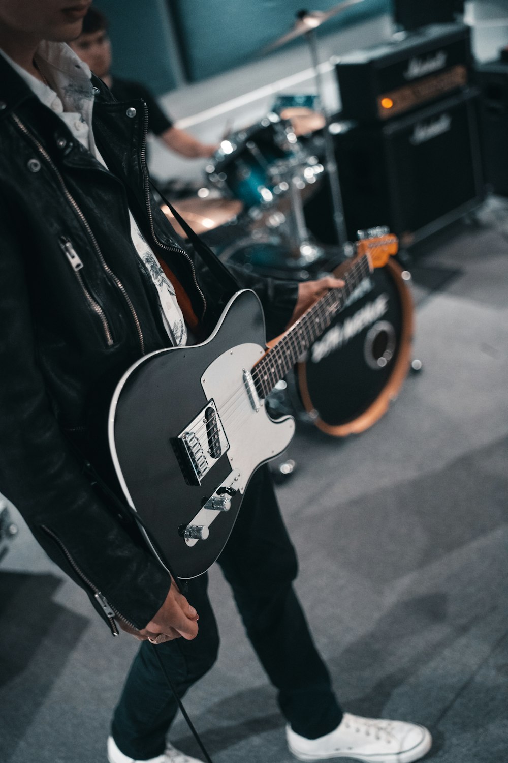 man in black leather jacket playing electric guitar