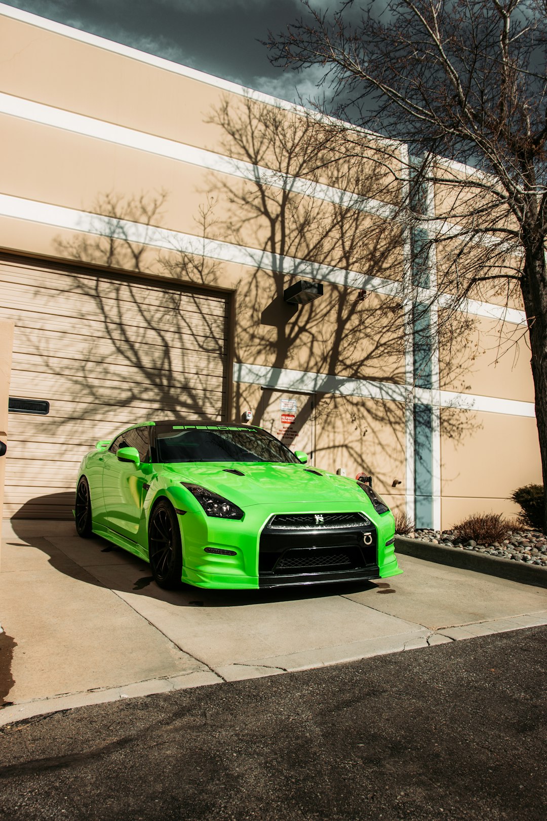 green car parked beside white building