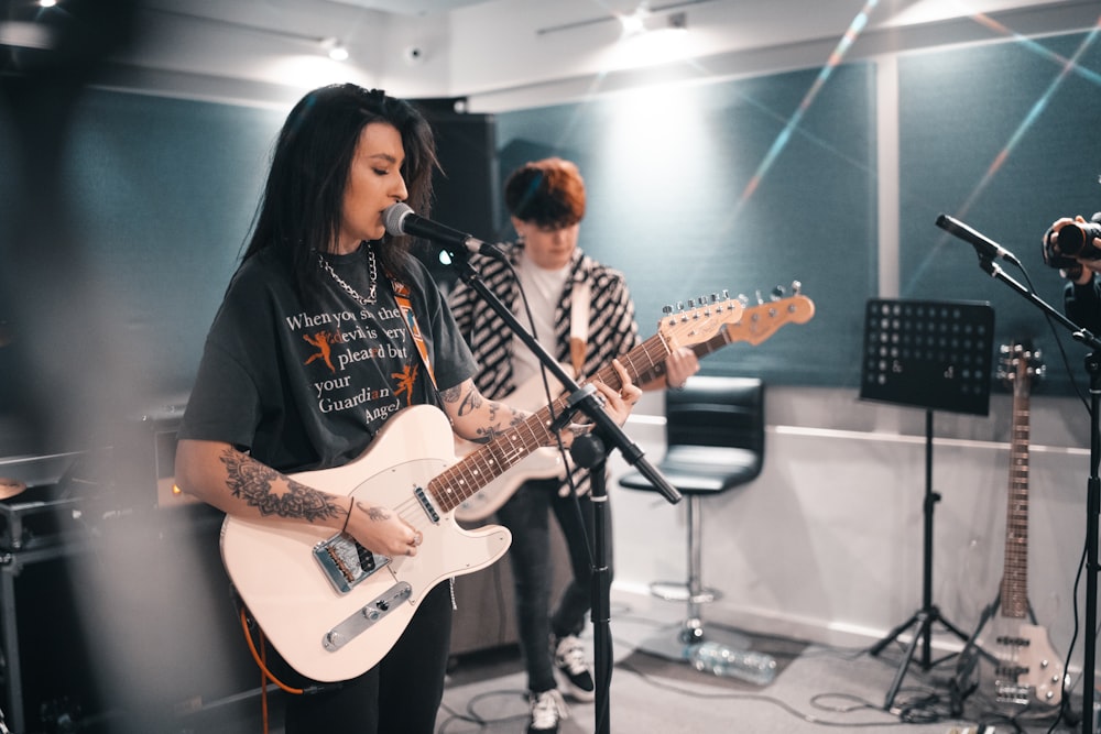 Two musicians in a studio playing royalty free music on guitar