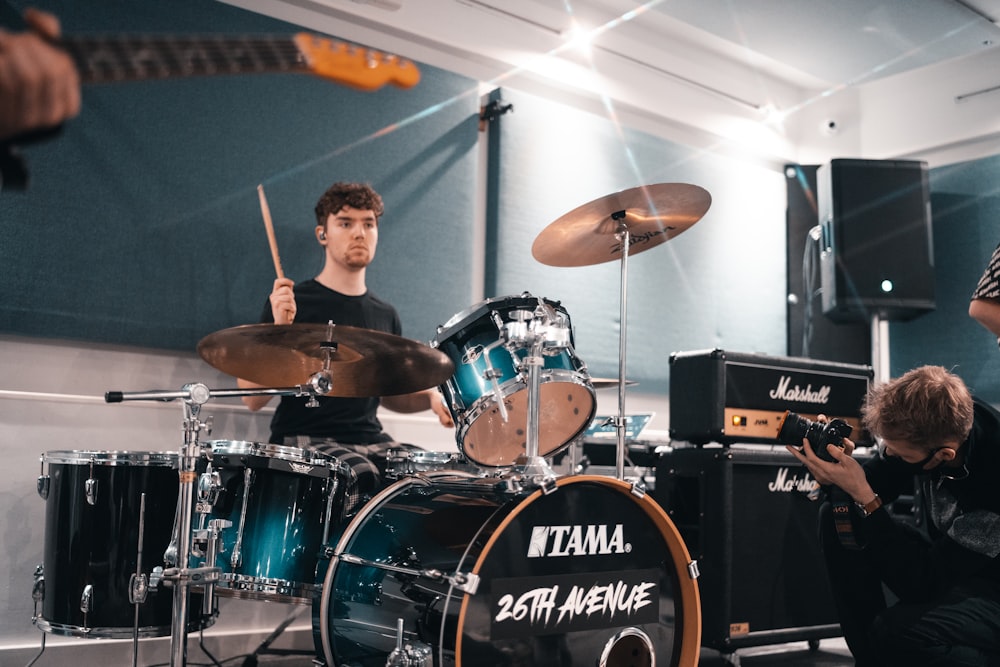 man in black shirt playing drum set