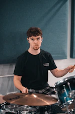 A focused student playing drums energetically in a modern music school room.