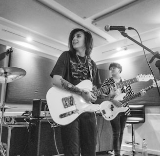 woman in black shirt playing white electric guitar