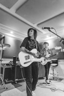 woman in black shirt playing white electric guitar