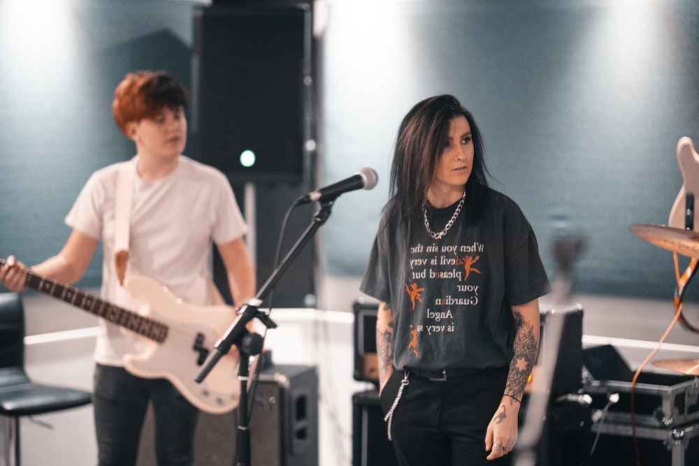 man in white crew neck t-shirt playing guitar beside woman in black long sleeve shirt