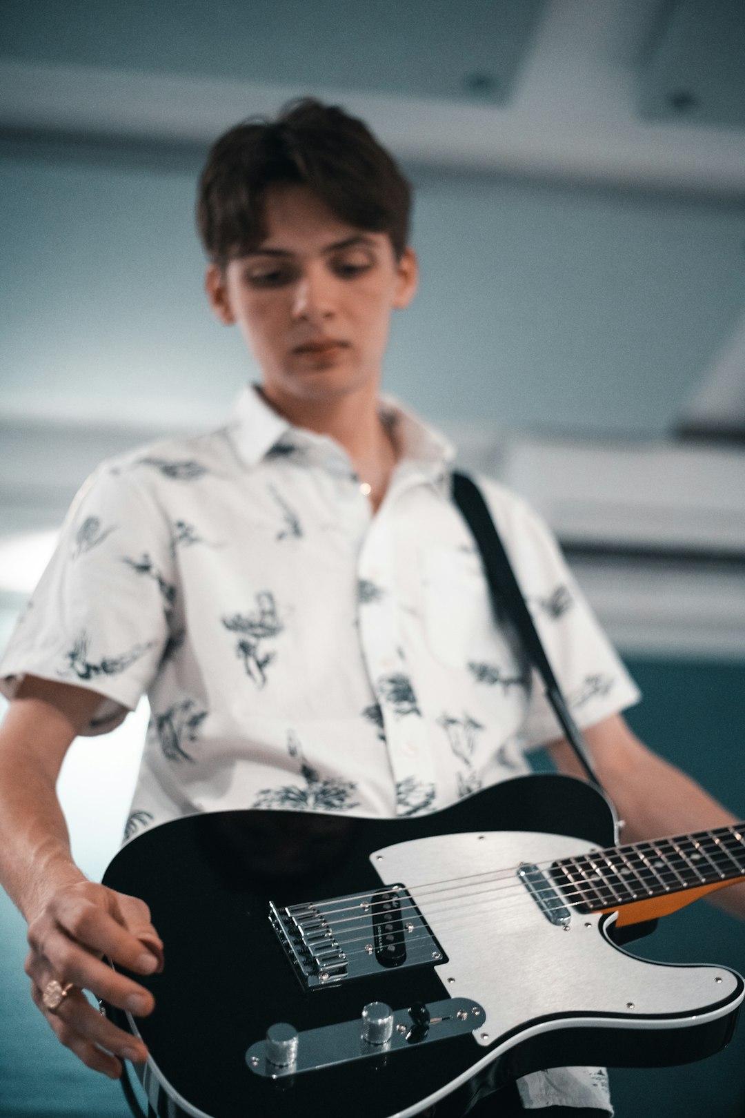 man in white and black floral button up shirt playing guitar
