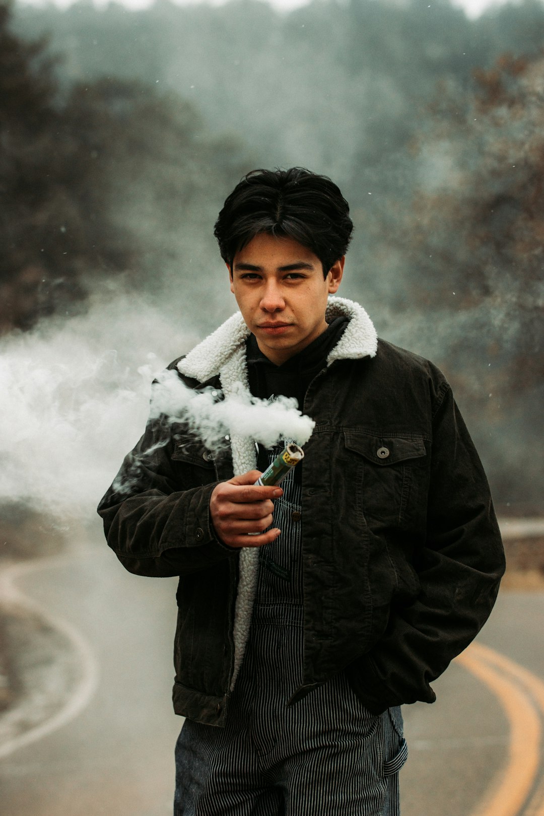 man in black jacket holding white smoke