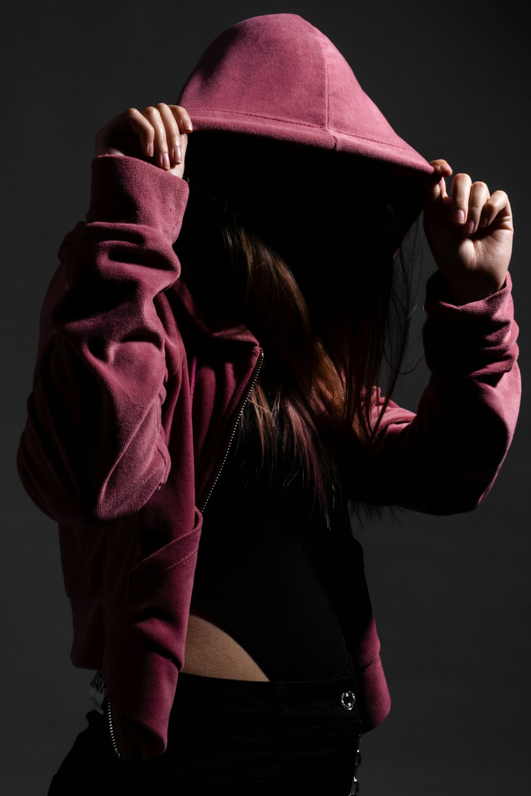 woman in pink hoodie covering her face with her hands