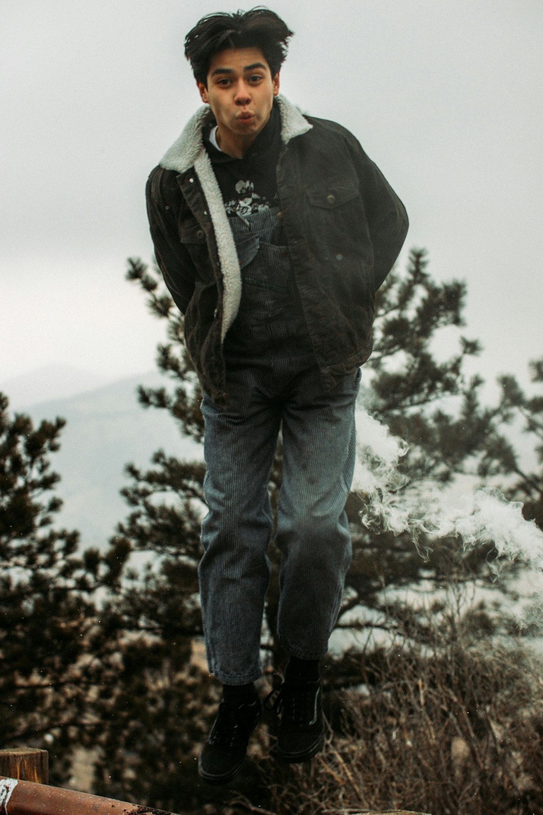 man in black jacket and blue denim jeans standing on rock during daytime