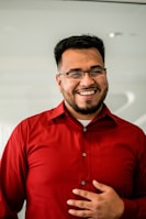 man in red button up shirt wearing black framed eyeglasses