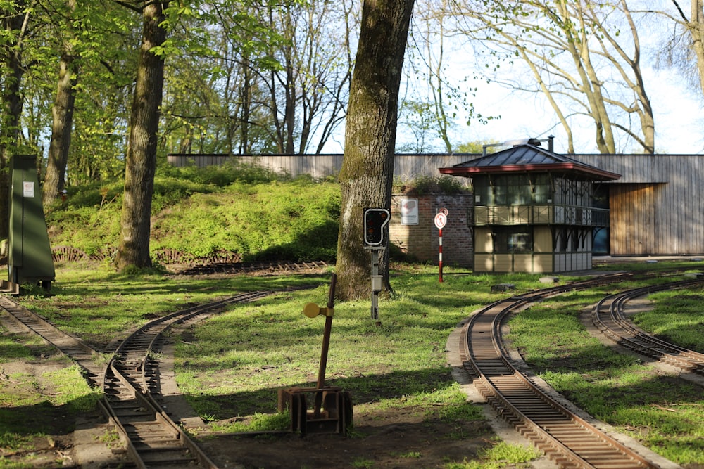 Braunes Holzhaus in der Nähe von Bäumen und Bahnschienen tagsüber