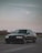 A sleek luxury car parked against a desert landscape under a twilight sky.