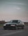 A sleek luxury car parked against a desert landscape under a twilight sky.