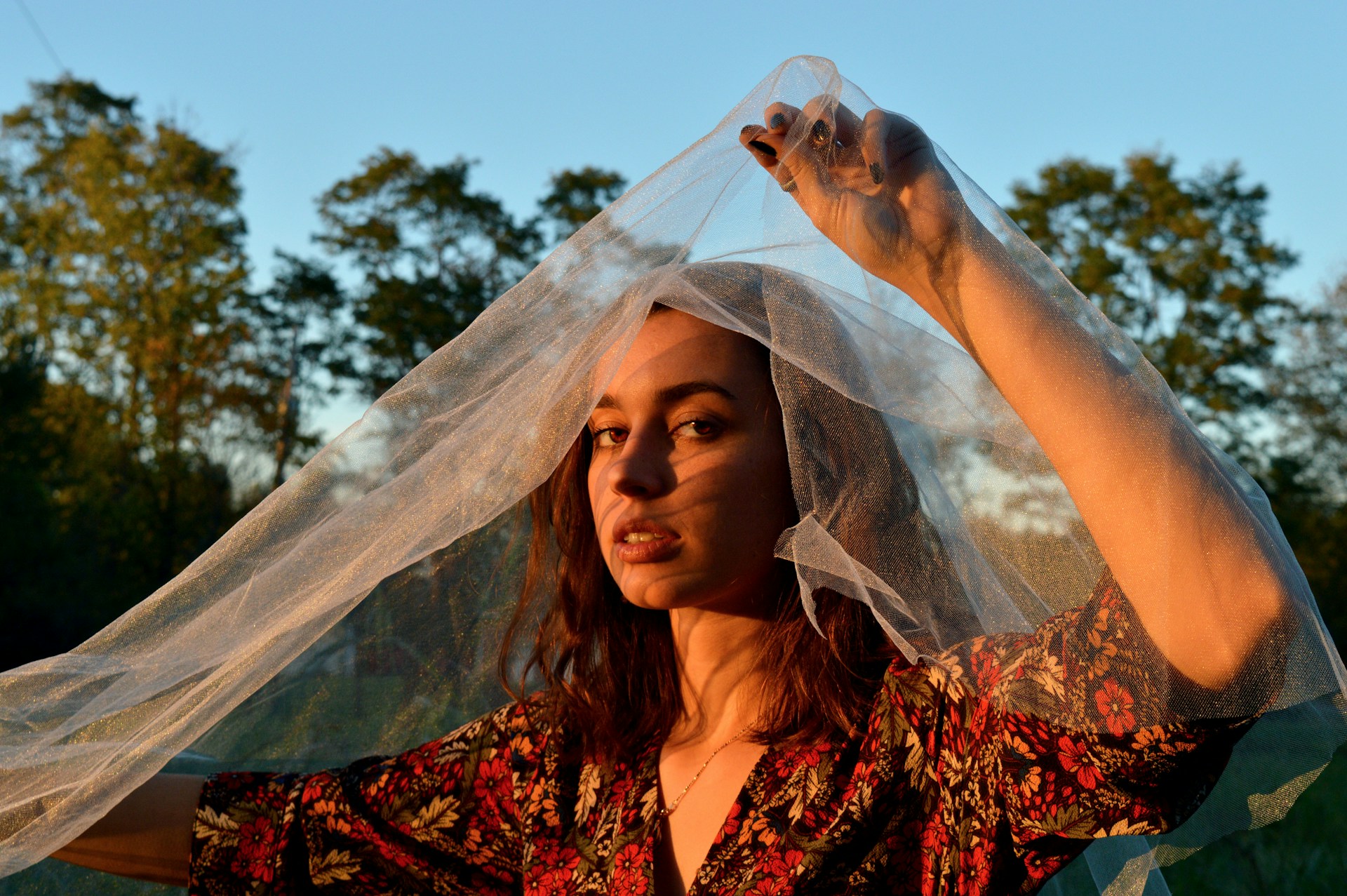 An elegant outdoor fashion scene at golden hour, showcasing flowing fabrics and natural light.