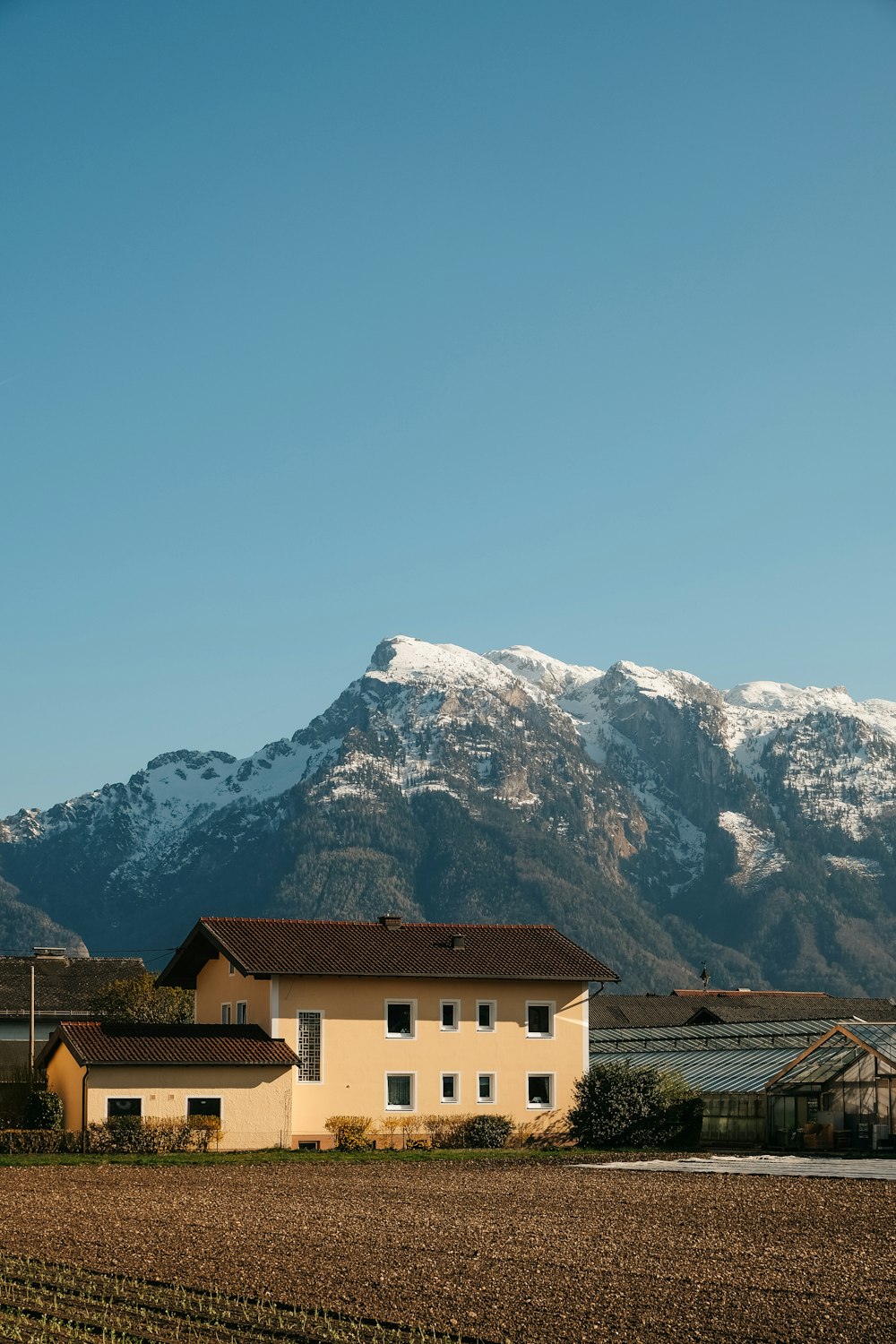 white and brown concrete house near snow covered mountain during daytime