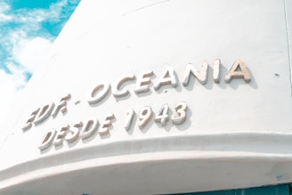 Large white text reads 'EDIF. OCEANIA DESDE 1943' on a curved pale wall under a bright, partly cloudy sky.