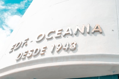 Large white text reads 'EDIF. OCEANIA DESDE 1943' on a curved pale wall under a bright, partly cloudy sky.