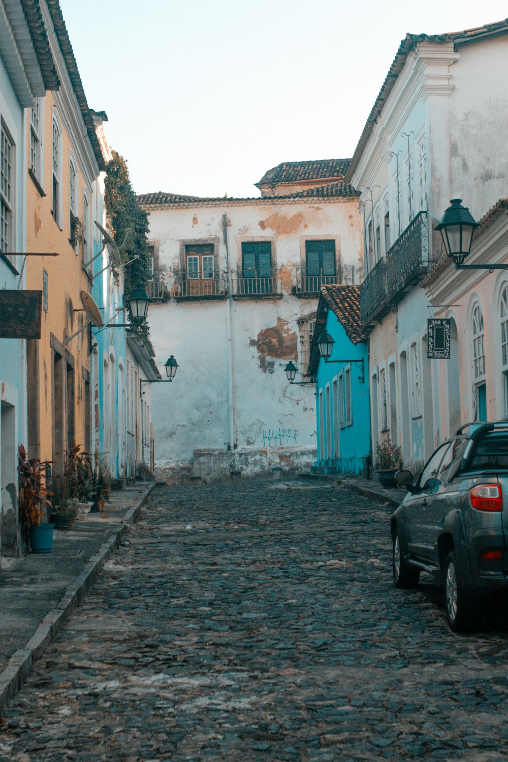 carro preto estacionado ao lado do edifício de concreto azul e branco durante o dia