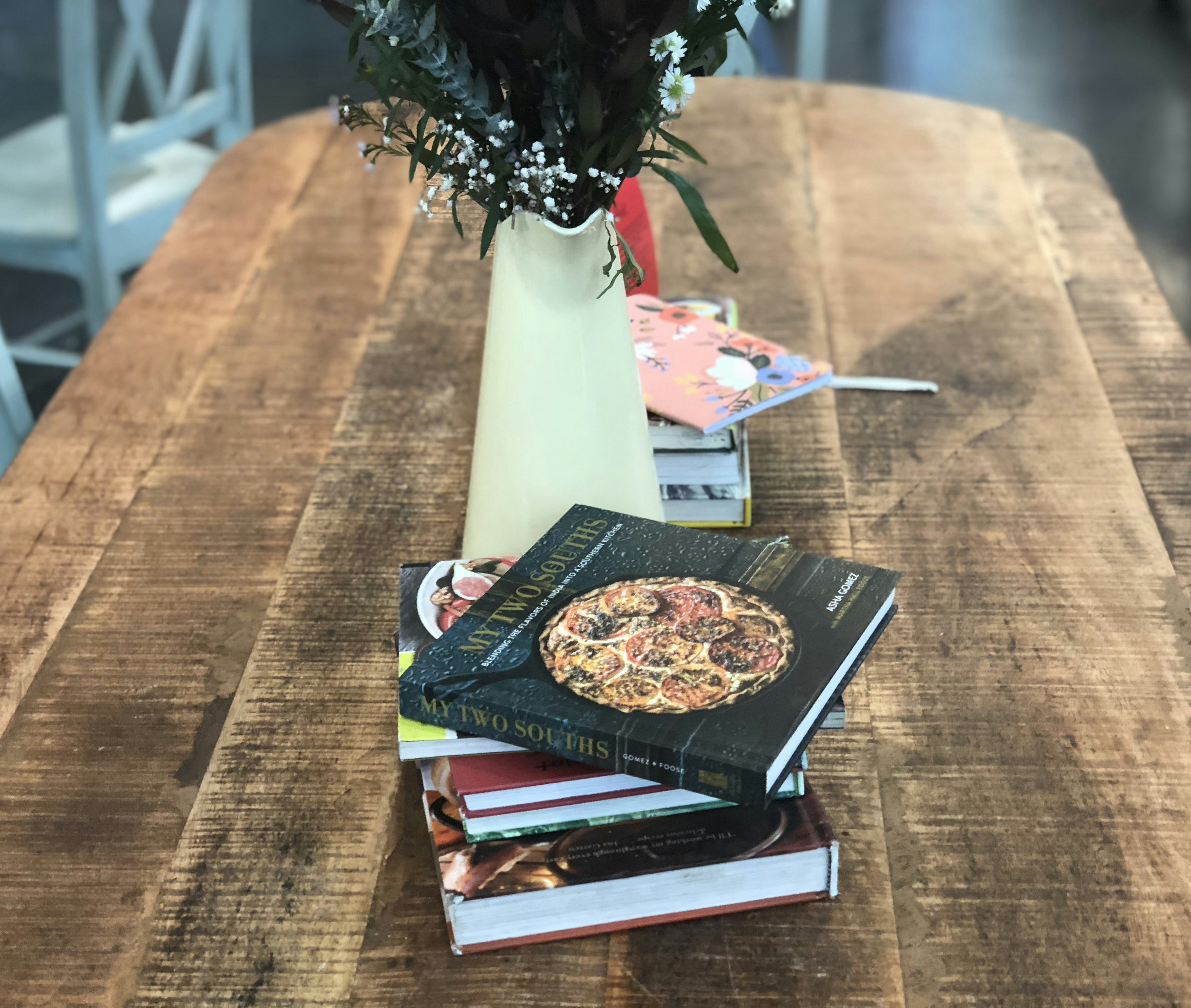 Stack of French culinary books on wooden table, warm natural light, bright airy setting