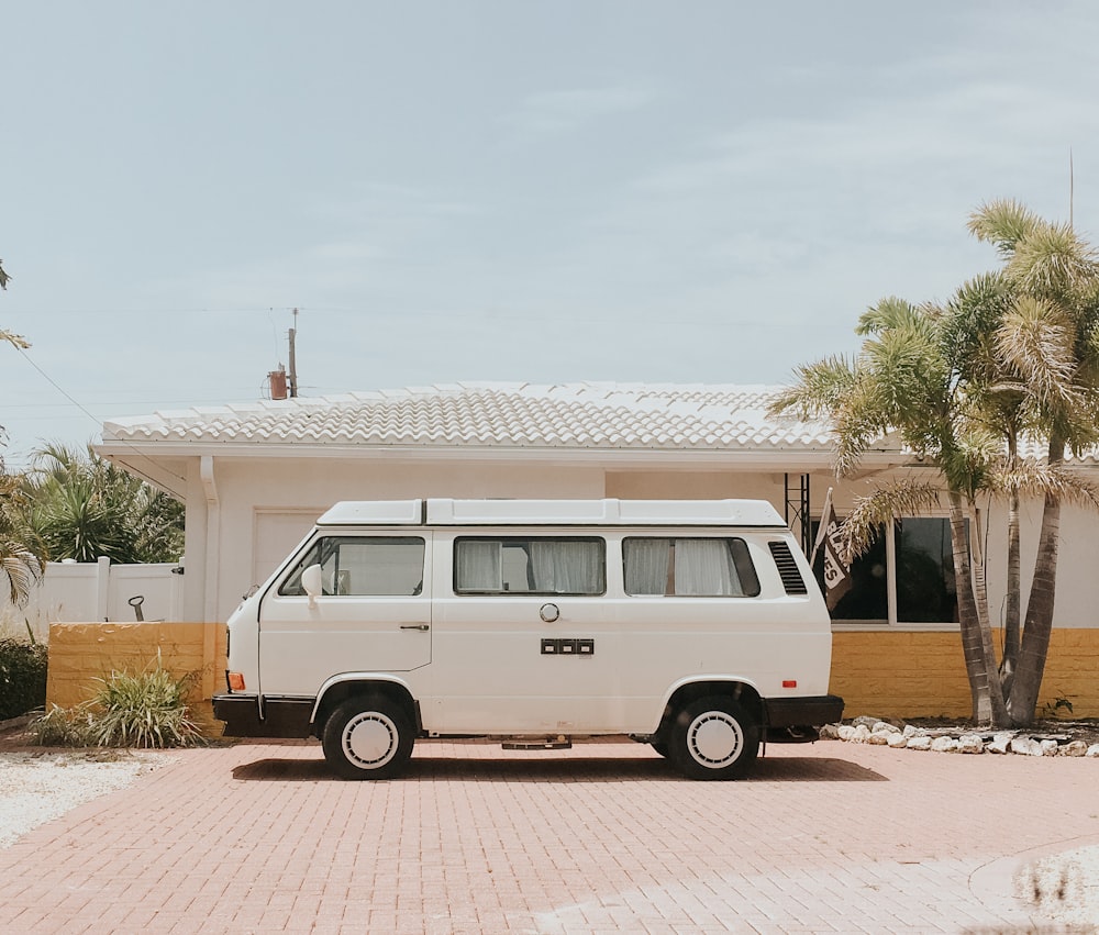 white van parked beside white and brown house