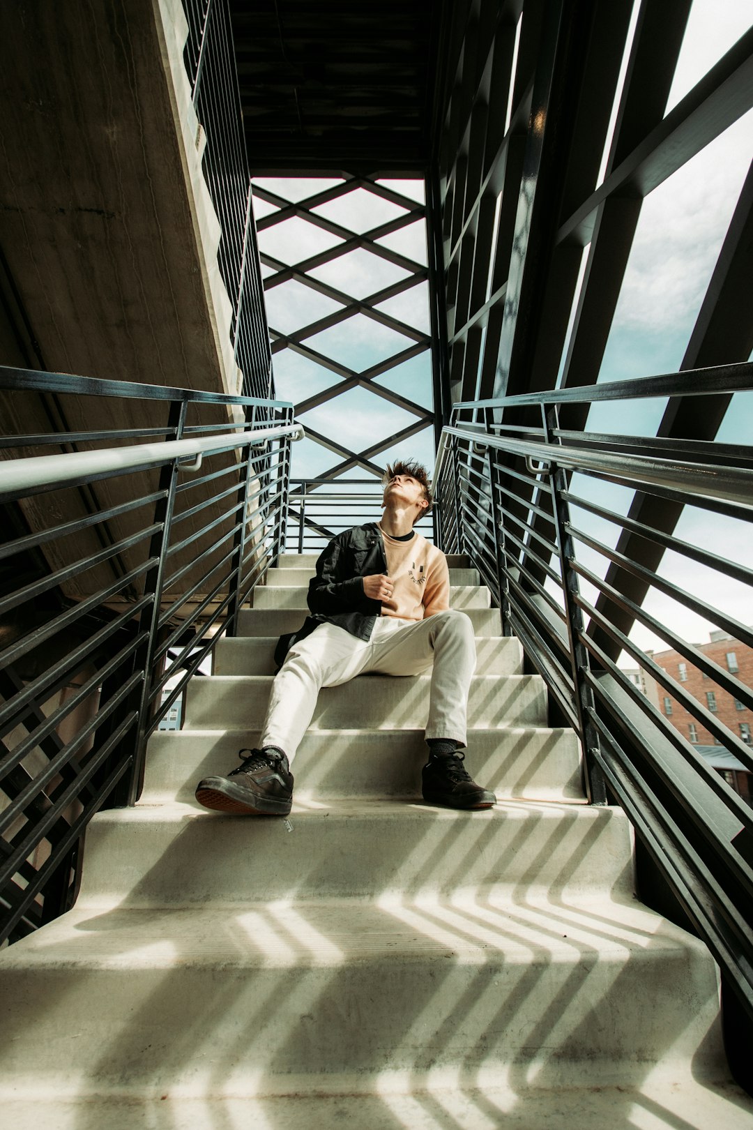 man in white dress shirt and white pants sitting on brown concrete staircase