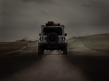 a jeep driving down a road under a cloudy sky