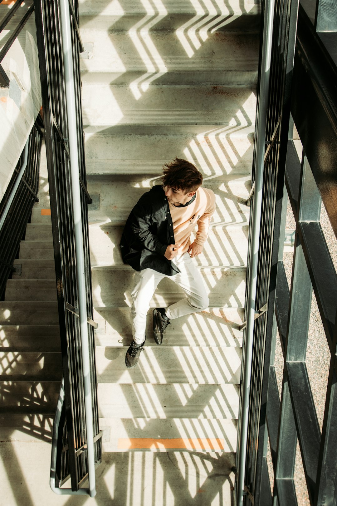 woman in black long sleeve shirt and white pants sitting on glass window