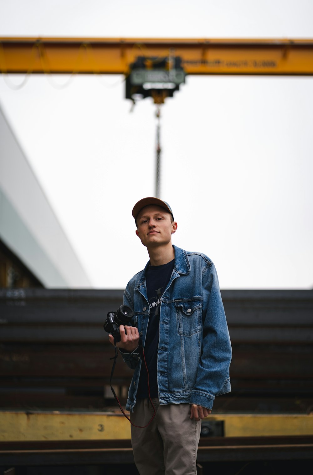 man in blue denim jacket holding black dslr camera