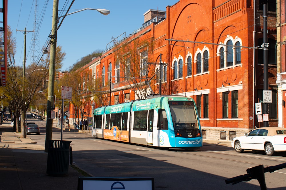 blue and white tram on road near brown building during daytime