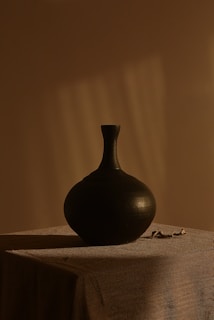 black ceramic vase on white textile