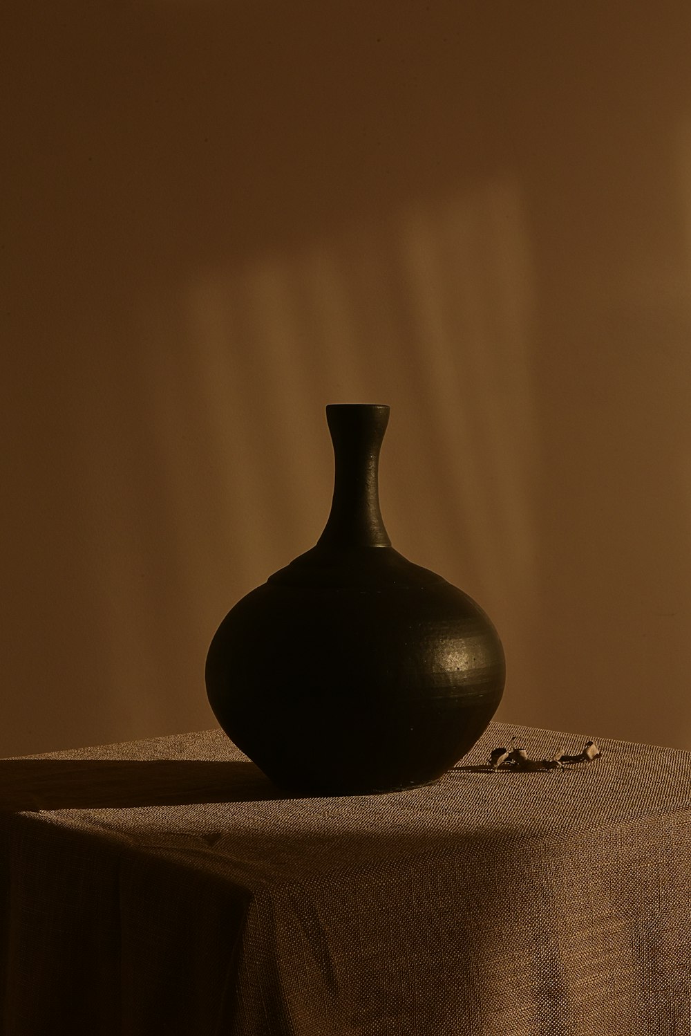 白い織物に黒い陶器の花瓶