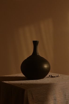 black ceramic vase on white textile