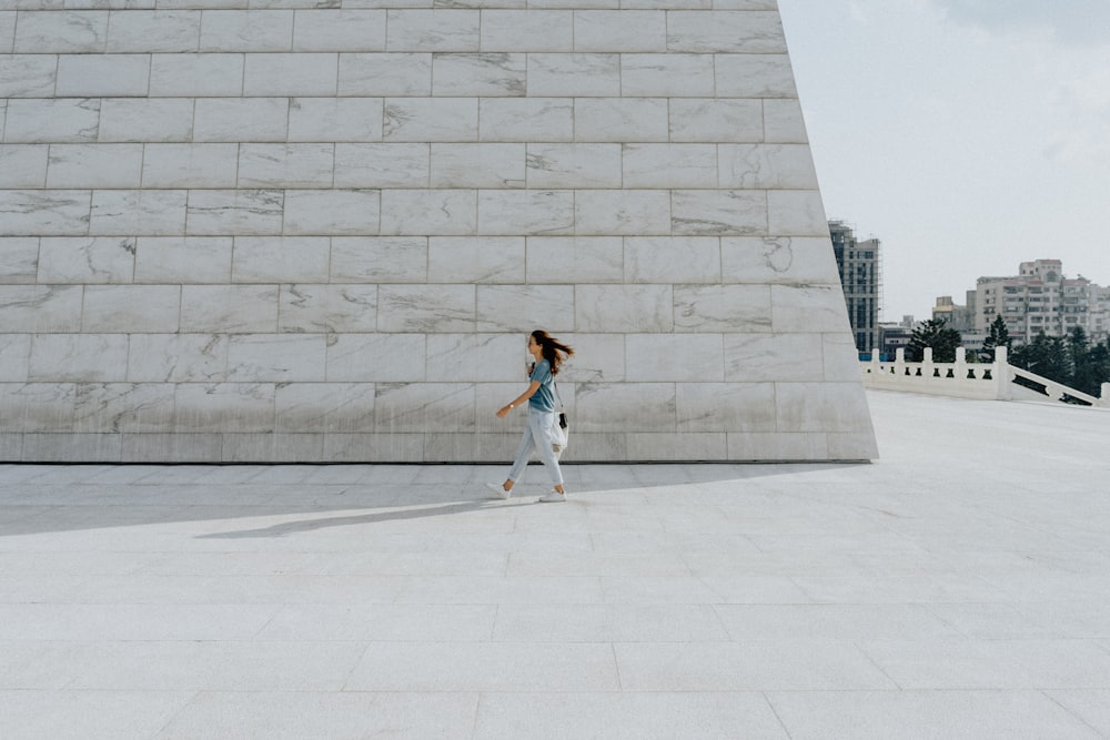 woman in white tank top and blue denim jeans standing on white concrete floor during daytime