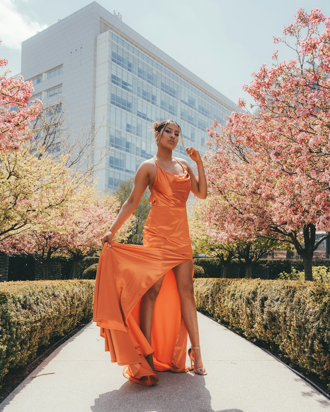 woman in orange tube dress standing on gray concrete pathway during daytime