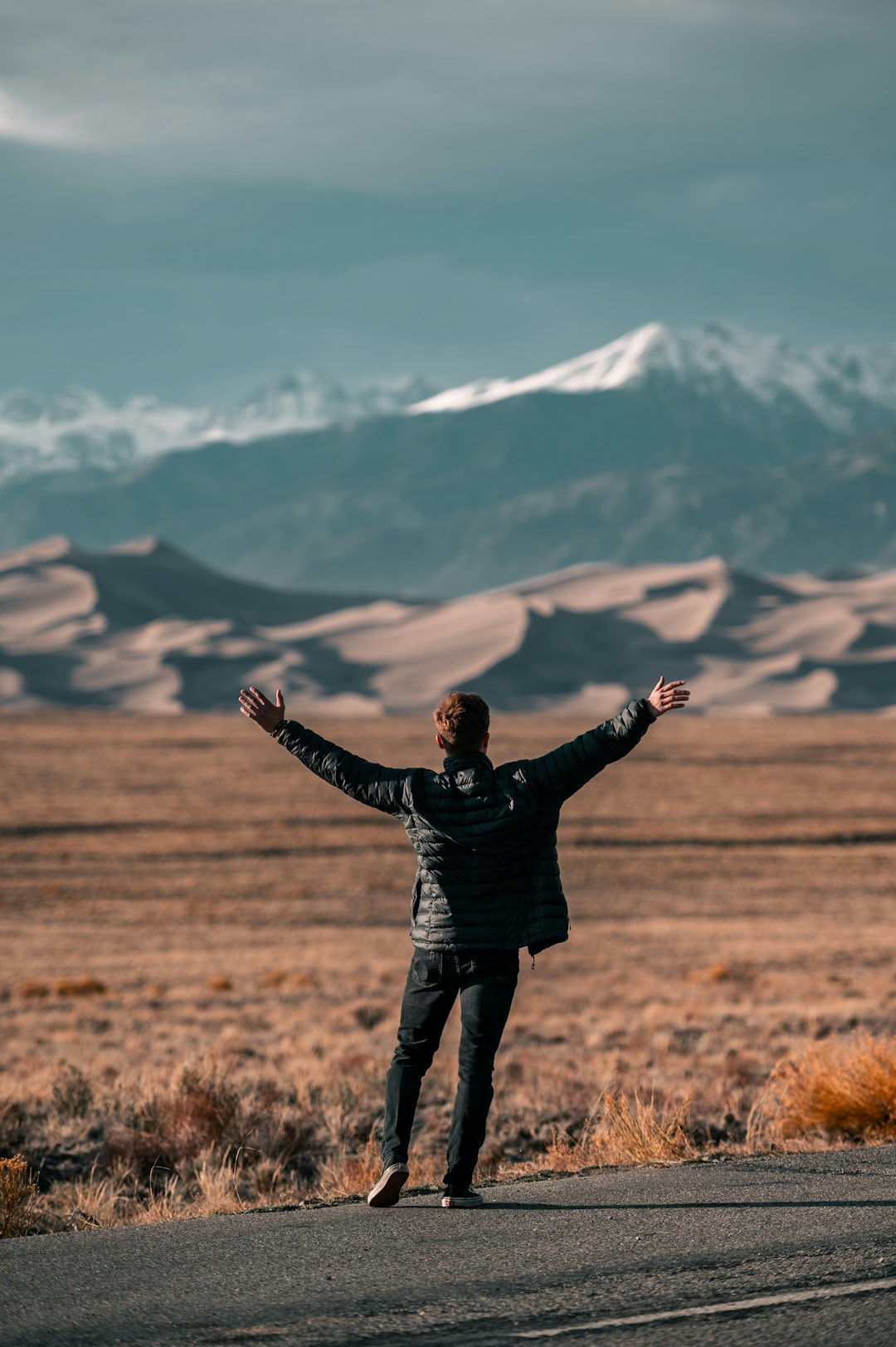 man in black jacket standing on brown grass field during daytime