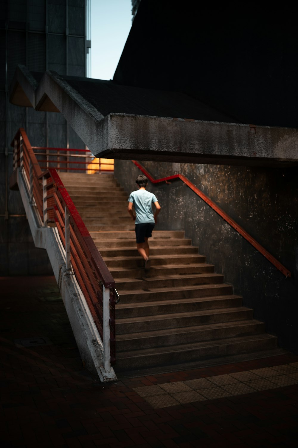 흰 셔츠와 빨간 바지를 입은 남자가 갈색 계단을 걷고 있다