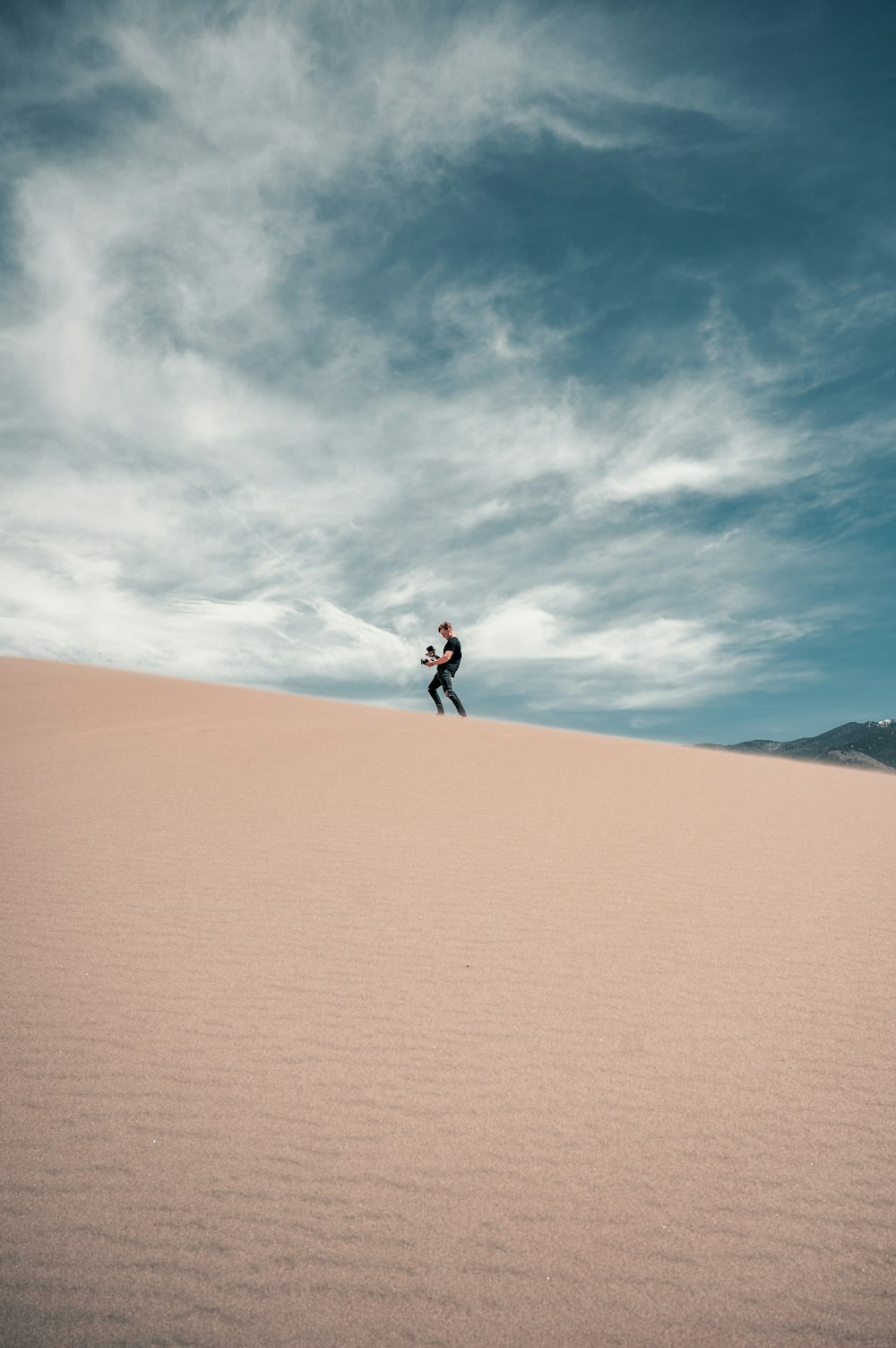 pessoa em jaqueta preta andando no deserto durante o dia