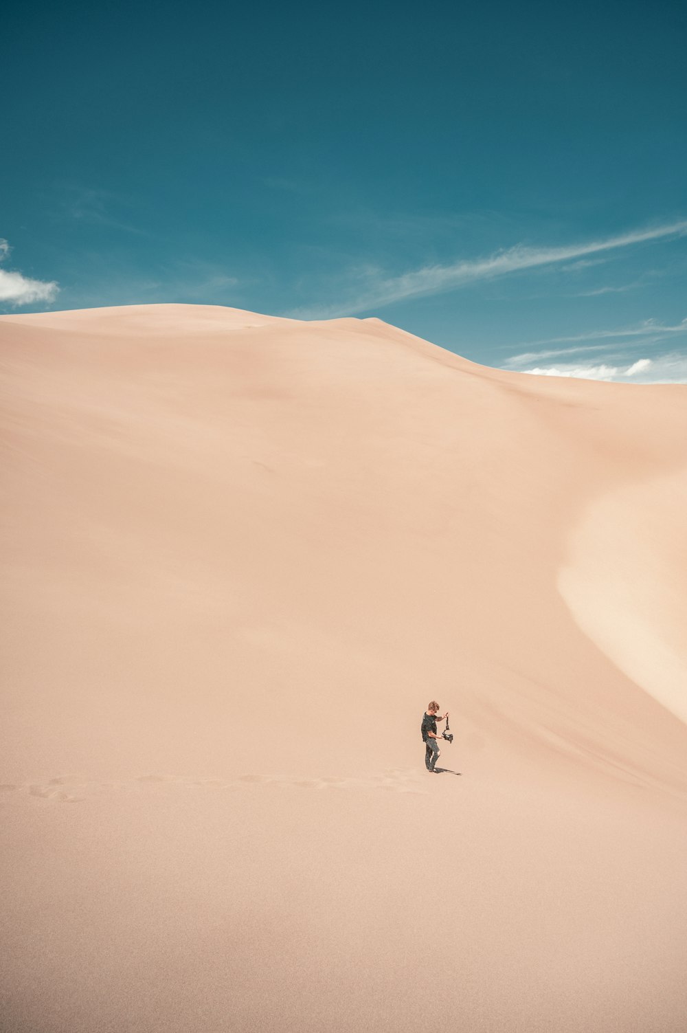 昼間の砂漠を歩く人