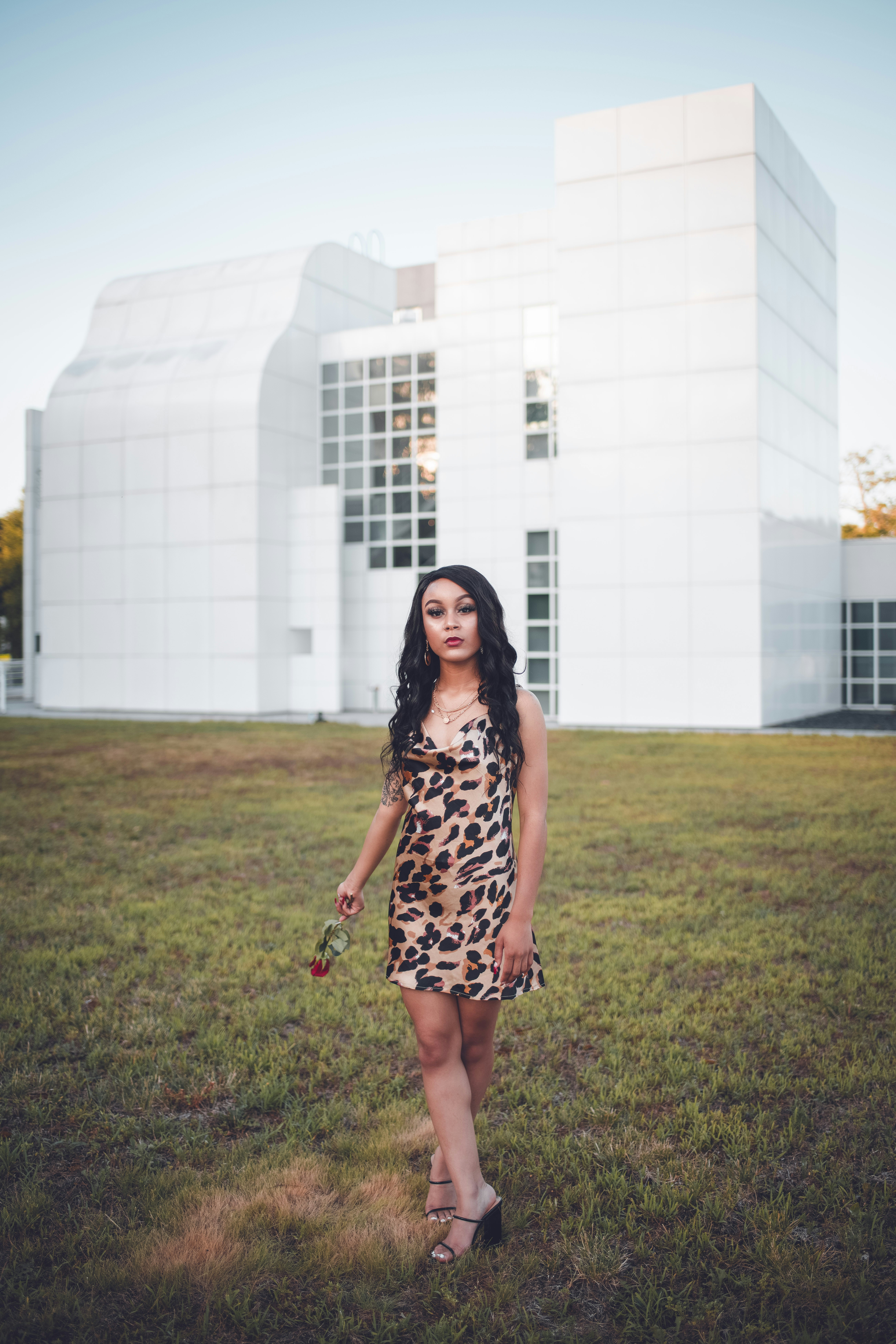 woman in black and white floral dress standing on green grass field