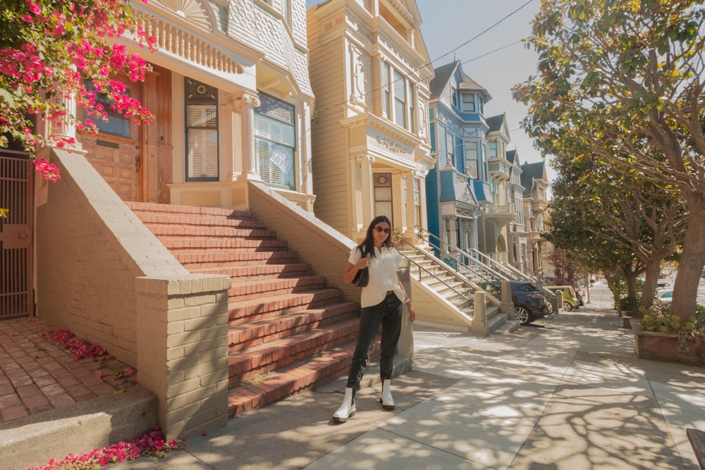 woman in white long sleeve shirt and black pants standing on gray concrete stairs during daytime