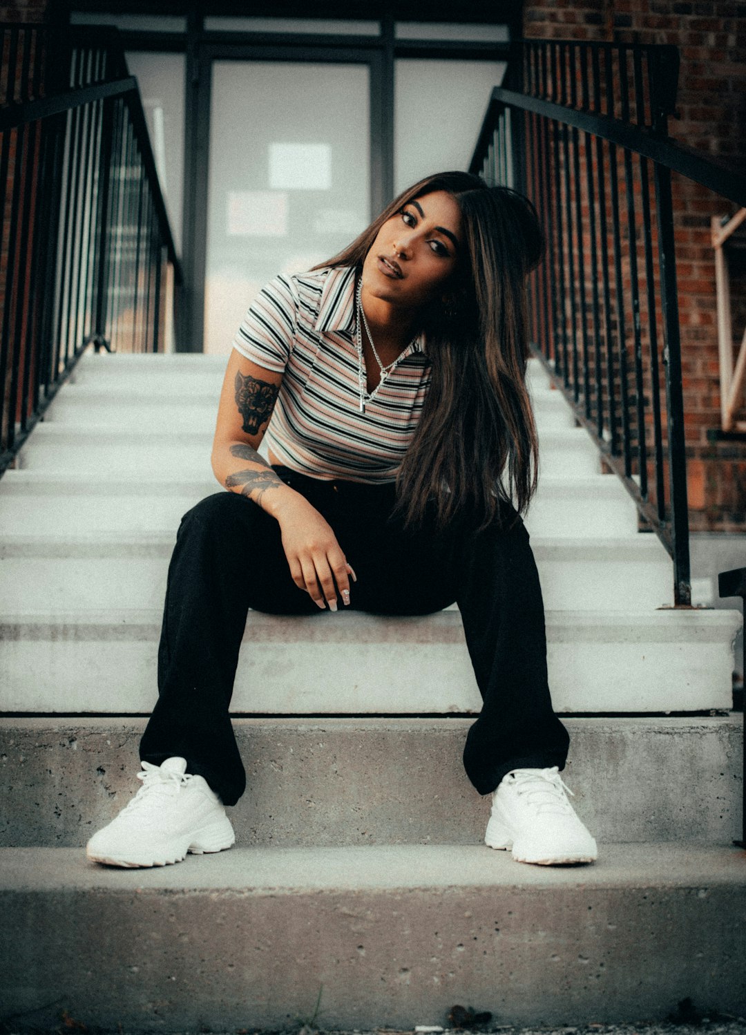 woman in black and white striped shirt and black pants sitting on concrete stairs