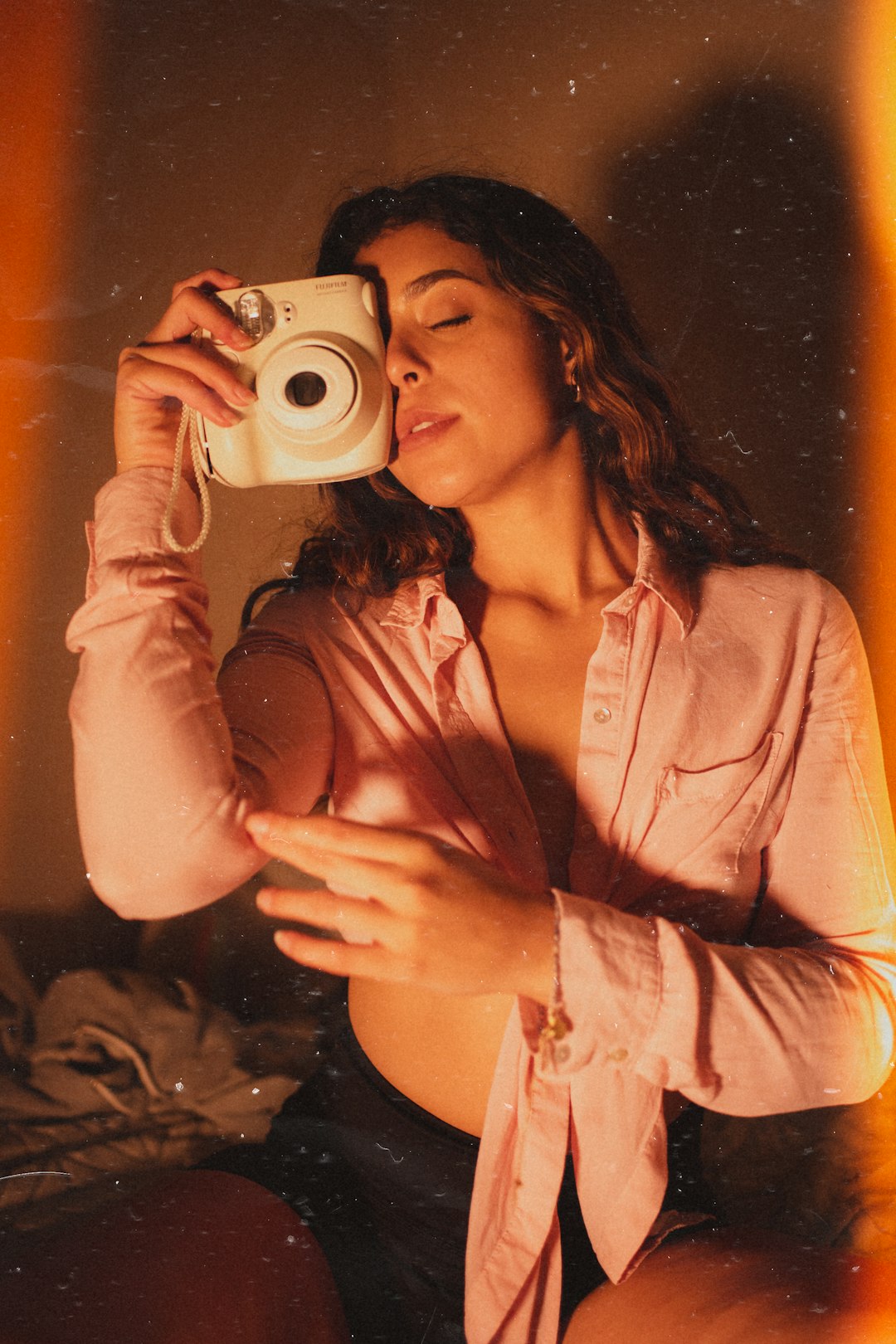 woman in pink dress shirt holding camera