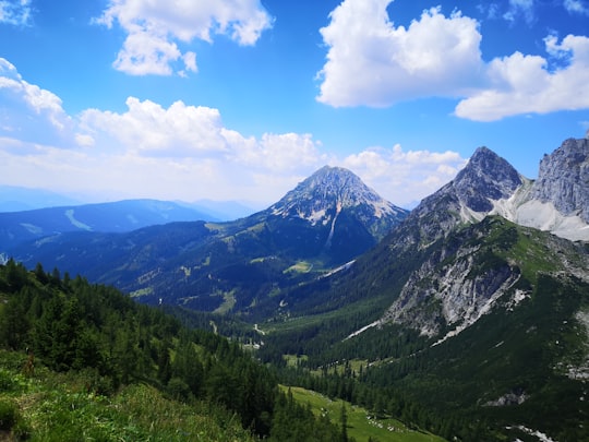 green trees and mountains under blue sky and white clouds during daytime in Hoher Dachstein Austria
