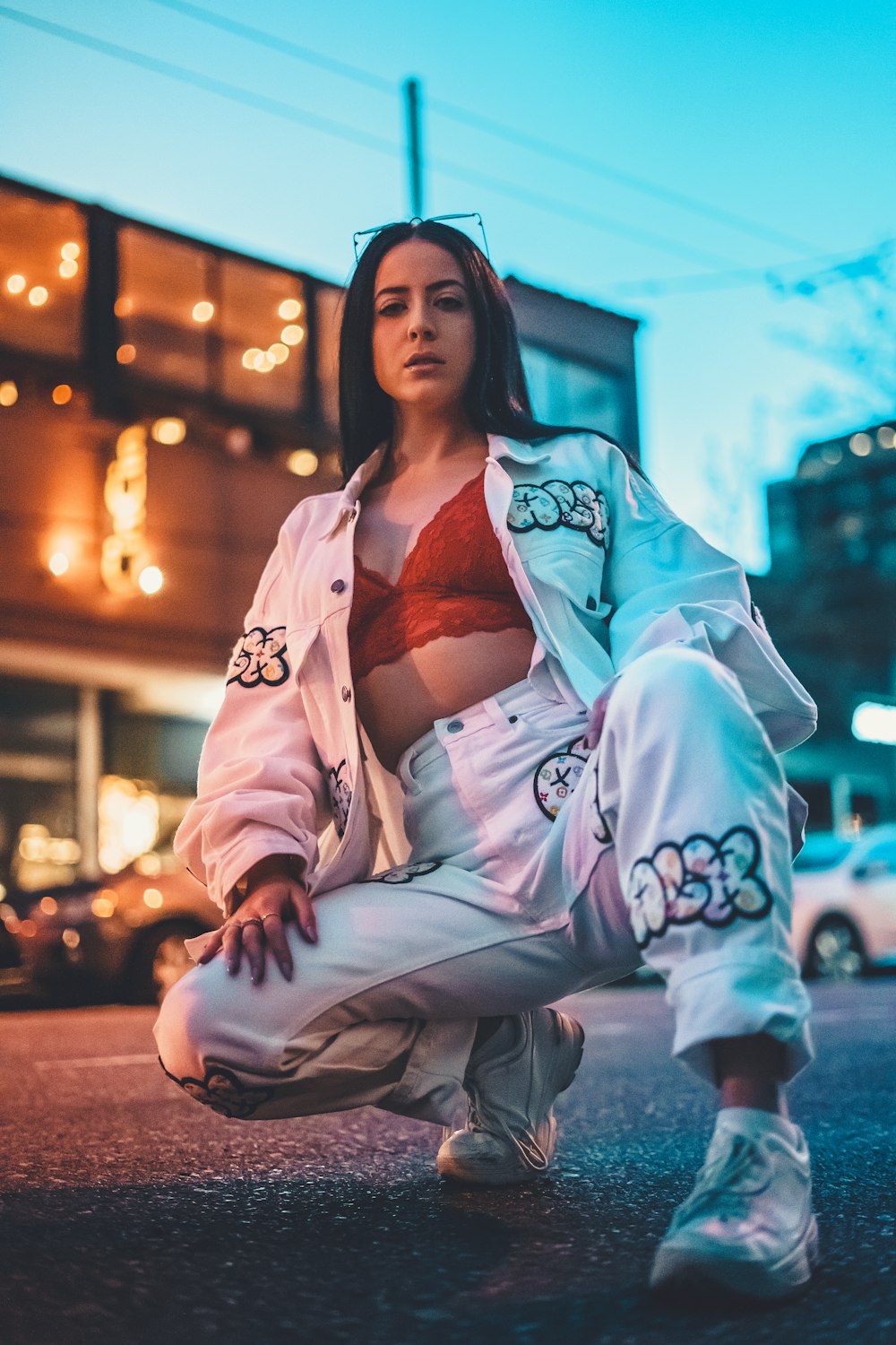 woman in white and brown floral coat sitting on brown concrete floor during night time